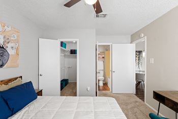 A bedroom with a bed, a ceiling fan, and a painting on the wall.